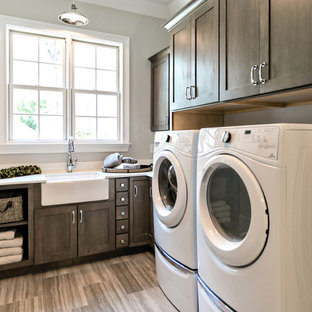 セントルイスの小さいトランジショナルスタイルのおしゃれな洗濯室 (エプロンフロントシンク、シェーカースタイル扉のキャビネット、濃色木目調キャビネット、グレーの壁、左右配置の洗濯機・乾燥機、ベージュの床、磁器タイルの床、クオーツストーンカウンター、白いキッチンカウンター) の写真