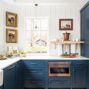 Immagine di una cucina country chiusa e di medie dimensioni con lavello stile country, ante a filo, ante blu, top in quarzo composito, paraspruzzi bianco, paraspruzzi in legno, elettrodomestici in acciaio inossidabile, parquet chiaro, pavimento giallo, top bianco e travi a vista