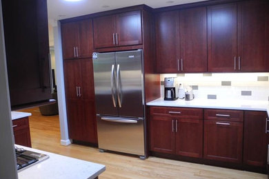 Eat-in kitchen - mid-sized contemporary u-shaped light wood floor and beige floor eat-in kitchen idea in DC Metro with shaker cabinets, dark wood cabinets, quartz countertops, white backsplash, subway tile backsplash, stainless steel appliances and a peninsula