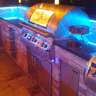 Design ideas for a mid-sized contemporary backyard patio in Miami with an outdoor kitchen, natural stone pavers and a gazebo/cabana.