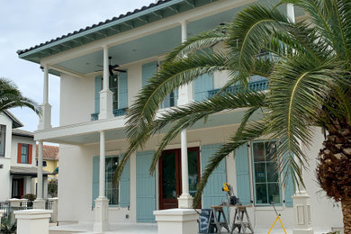 Large beach style white three-story stucco house exterior photo in Other with a tile roof
