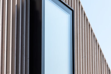 Contemporary two floor house exterior in Channel Islands with wood cladding, a pitched roof and board and batten cladding.