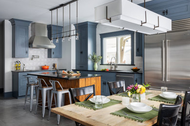 Example of a mid-sized eclectic l-shaped porcelain tile and gray floor kitchen design in New York with an undermount sink, recessed-panel cabinets, blue cabinets, soapstone countertops, white backsplash, stainless steel appliances, an island and black countertops