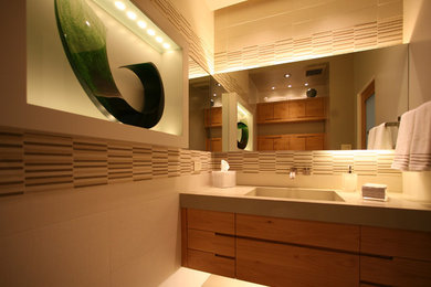 Photo of a contemporary bathroom in Portland with engineered quartz benchtops, an integrated sink, flat-panel cabinets, medium wood cabinets, a wall-mount toilet, beige tile, ceramic tile, white walls and porcelain floors.