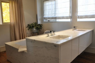 Drop-in bathtub - large contemporary master white tile medium tone wood floor drop-in bathtub idea in Ottawa with an undermount sink, flat-panel cabinets, white cabinets, marble countertops, a one-piece toilet and gray walls