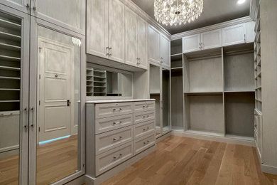 Inspiration for a large coastal women's light wood floor and brown floor walk-in closet remodel in Chicago with recessed-panel cabinets and light wood cabinets