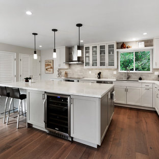 Réalisation d'une arrière-cuisine tradition en L de taille moyenne avec un évier encastré, un placard à porte shaker, des portes de placard blanches, un plan de travail en quartz modifié, une crédence beige, une crédence en carrelage métro, un électroménager en acier inoxydable, un sol en bois brun, un îlot central, un sol marron et un plan de travail beige.