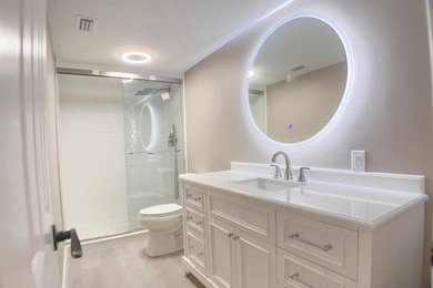 マイアミにある高級な中くらいなモダンスタイルのおしゃれな浴室 (落し込みパネル扉のキャビネット、オープン型シャワー、分離型トイレ、白いタイル、ベージュの壁、クッションフロア、アンダーカウンター洗面器、クオーツストーンの洗面台、ベージュの床、引戸のシャワー、白い洗面カウンター、洗面台1つ、独立型洗面台) の写真