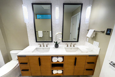 Mid-sized transitional master beige tile and ceramic tile porcelain tile, gray floor and double-sink bathroom photo in Portland with flat-panel cabinets, medium tone wood cabinets, a one-piece toilet, beige walls, an undermount sink, solid surface countertops, a hinged shower door, white countertops, a niche and a floating vanity