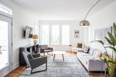 Trendy medium tone wood floor living room photo in Other with white walls and a wall-mounted tv