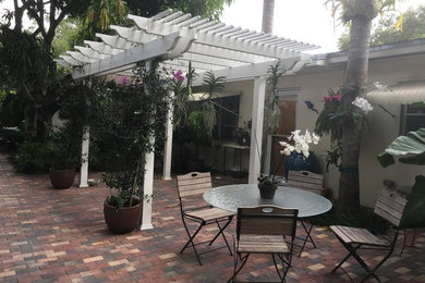 This is an example of a small mediterranean courtyard patio in Miami with a vertical garden, brick pavers and a pergola.