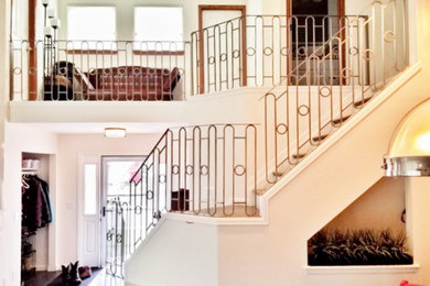 Large carpeted curved metal railing staircase photo in Denver with wooden risers