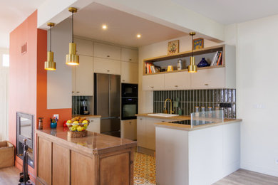 Cette image montre une cuisine vintage avec un plan de travail en bois, une crédence verte, carreaux de ciment au sol, 2 îlots et un plan de travail beige.