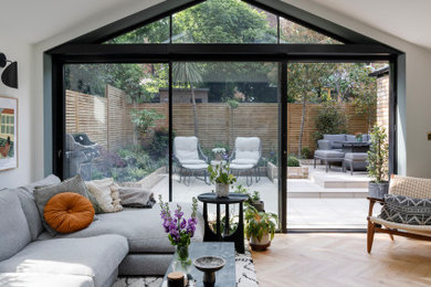 Design ideas for a medium sized contemporary grey and white living room in London with white walls, light hardwood flooring, a wall mounted tv, beige floors and a vaulted ceiling.