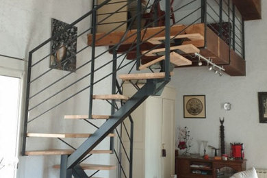 Foto de escalera curva actual pequeña con escalones de madera y barandilla de metal