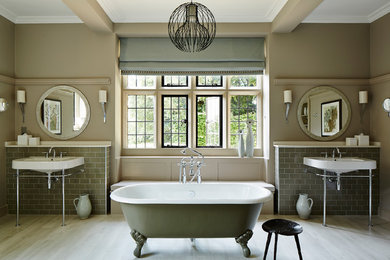 Inspiration for a mid-sized traditional master bathroom in London with gray tile, subway tile, a claw-foot tub, a shower/bathtub combo, beige walls, light hardwood floors, a console sink, beige floor and an open shower.