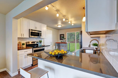 Inspiration for a mid-sized transitional u-shaped dark wood floor enclosed kitchen remodel in San Luis Obispo with an undermount sink, shaker cabinets, white cabinets, white backsplash, subway tile backsplash, stainless steel appliances and a peninsula