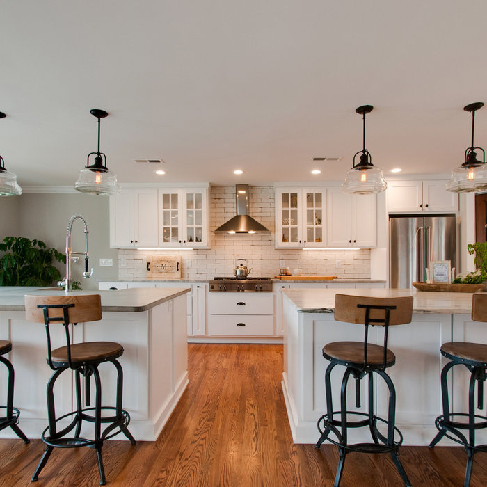 Heres a closer angle of the kitchen only.  Details such as schoolhouse pendants, an industrial faucet and distressed brick subway tile creates a simple yet strong farmhouse statement.