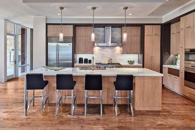 This is an example of a contemporary kitchen in Dallas with flat-panel cabinets, light wood cabinets, white splashback, marble splashback, stainless steel appliances, medium hardwood floors and with island.