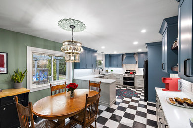 Example of a mid-sized eclectic u-shaped marble floor and black floor eat-in kitchen design in Detroit with an undermount sink, shaker cabinets, blue cabinets, quartz countertops, white backsplash, subway tile backsplash, stainless steel appliances, a peninsula and white countertops