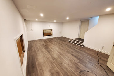 Ejemplo de sótano en el subsuelo minimalista de tamaño medio con paredes blancas, suelo vinílico y suelo marrón