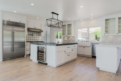 Inspiration for a mid-sized contemporary u-shaped eat-in kitchen remodel in Santa Barbara with recessed-panel cabinets, white cabinets and an island