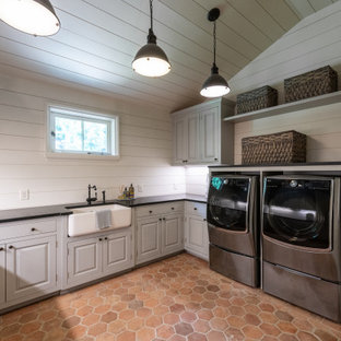 Idee per una grande sala lavanderia design con lavello stile country, ante lisce, ante grigie, top in granito, paraspruzzi beige, paraspruzzi in perlinato, pareti beige, pavimento in terracotta, lavatrice e asciugatrice affiancate, top nero, soffitto in perlinato e pareti in perlinato