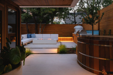 Imagen de jardín moderno pequeño en patio trasero con brasero, exposición parcial al sol, adoquines de hormigón y con madera