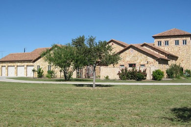 Large tuscan beige two-story stone exterior home photo in Austin with a tile roof