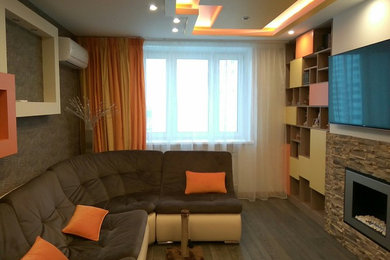 Свежая идея для дизайна: изолированная гостиная комната среднего размера в современном стиле с бежевыми стенами, полом из ламината, стандартным камином, фасадом камина из камня, телевизором на стене и коричневым полом - отличное фото интерьера