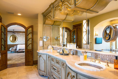 Drop-in bathtub - large traditional master brown tile and porcelain tile limestone floor drop-in bathtub idea in Santa Barbara with raised-panel cabinets