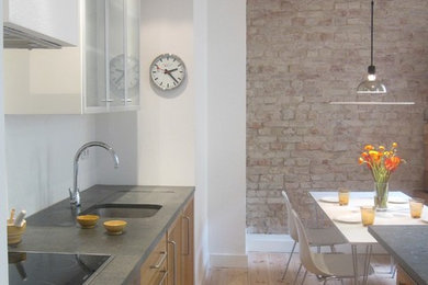 Photo of a contemporary kitchen/diner in Berlin with medium wood cabinets, limestone worktops, stainless steel appliances, light hardwood flooring, an island and a submerged sink.