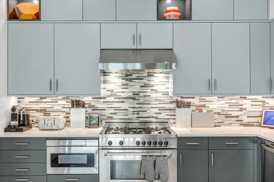 Esempio di una cucina a L moderna con ante lisce, ante verdi, top in quarzo composito, elettrodomestici in acciaio inossidabile e top bianco