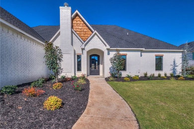 Example of a huge country white one-story brick house exterior design in Oklahoma City with a gambrel roof and a shingle roof