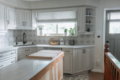 Mid-sized minimalist l-shaped enclosed kitchen photo in Toronto with a single-bowl sink, shaker cabinets, gray cabinets, quartz countertops, blue backsplash, cement tile backsplash, stainless steel appliances, an island and white countertops