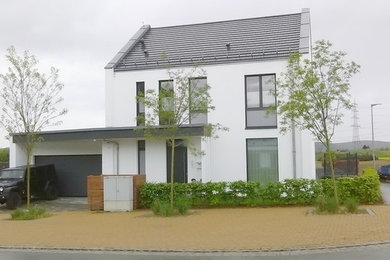 Ejemplo de fachada de casa actual de tamaño medio de dos plantas con revestimiento de estuco y tejado de teja de barro