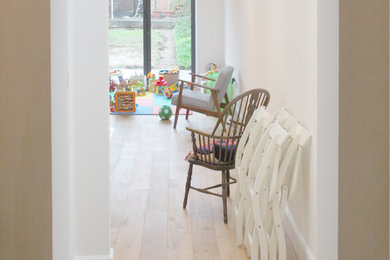 Inspiration for a small modern open plan living room in London with white walls, light hardwood flooring, no fireplace and beige floors.