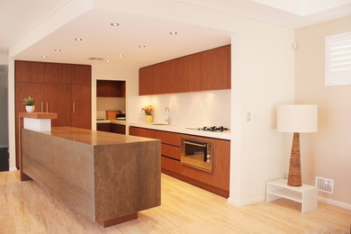 Inspiration for a mid-sized modern u-shaped open plan kitchen in Perth with a double-bowl sink, flat-panel cabinets, brown cabinets, solid surface benchtops, white splashback, stone slab splashback, panelled appliances, marble floors and with island.