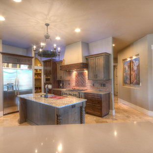 Inspiration pour une arrière-cuisine chalet en U de taille moyenne avec un évier de ferme, un placard à porte shaker, un plan de travail en granite, une crédence rouge, une crédence en brique, un électroménager en acier inoxydable, un sol en travertin, un îlot central, un sol beige, des portes de placard grises et un plan de travail multicolore.