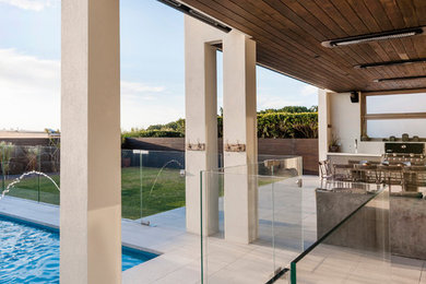 Inspiration for a large modern backyard tile patio kitchen remodel with a roof extension