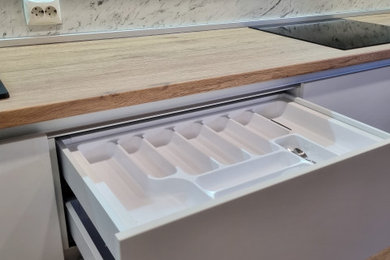 Modelo de cocina blanca y madera escandinava de tamaño medio con fregadero encastrado, encimera de laminado y electrodomésticos con paneles
