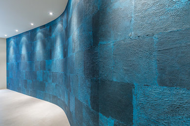 Réalisation d'un couloir design avec un mur bleu, un sol en carrelage de céramique et un sol beige.