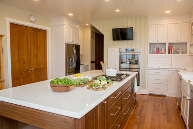 Inspiration for a mid-sized transitional l-shaped medium tone wood floor eat-in kitchen remodel in DC Metro with a farmhouse sink, flat-panel cabinets, quartz countertops, white backsplash, mosaic tile backsplash and an island