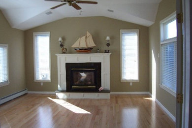 Mid-sized traditional enclosed family room in New York with beige walls, light hardwood floors and a standard fireplace.