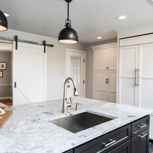 Idée de décoration pour une grande arrière-cuisine champêtre avec un évier encastré, un placard avec porte à panneau encastré, des portes de placard blanches, un plan de travail en granite, une crédence blanche, une crédence en carreau de porcelaine, un électroménager encastrable, un sol en carrelage de porcelaine et un îlot central.