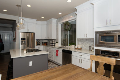 This is an example of a mid-sized transitional l-shaped eat-in kitchen in Seattle with an undermount sink, shaker cabinets, white cabinets, grey splashback, marble splashback, stainless steel appliances, dark hardwood floors, with island, brown floor and beige benchtop.