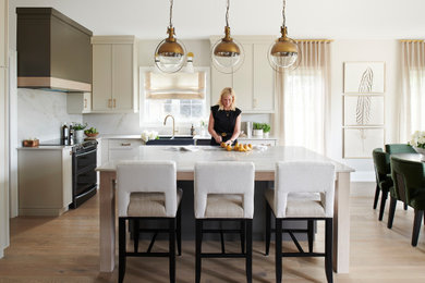 Large transitional l-shaped light wood floor and beige floor eat-in kitchen photo in Other with a farmhouse sink, shaker cabinets, beige cabinets, quartzite countertops, white backsplash, granite backsplash, black appliances, an island and white countertops