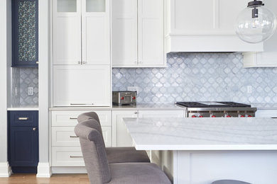 Large transitional l-shaped medium tone wood floor and brown floor open concept kitchen photo in Toronto with a farmhouse sink, shaker cabinets, white cabinets, quartz countertops, white backsplash, marble backsplash, stainless steel appliances, an island and multicolored countertops