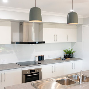 Inspiration för mellanstora moderna grått kök, med en dubbel diskho, skåp i shakerstil, vita skåp, laminatbänkskiva, vitt stänkskydd, stänkskydd i keramik, rostfria vitvaror, cementgolv, en köksö och grått golv