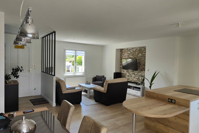 Imagen de sala de estar actual de tamaño medio sin chimenea con paredes blancas, suelo de madera clara y televisor colgado en la pared